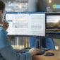 Analyst Works on a Personal Computer Showing Statistics, Graphs and Charts. In the Background His Coworker and Creative Office.